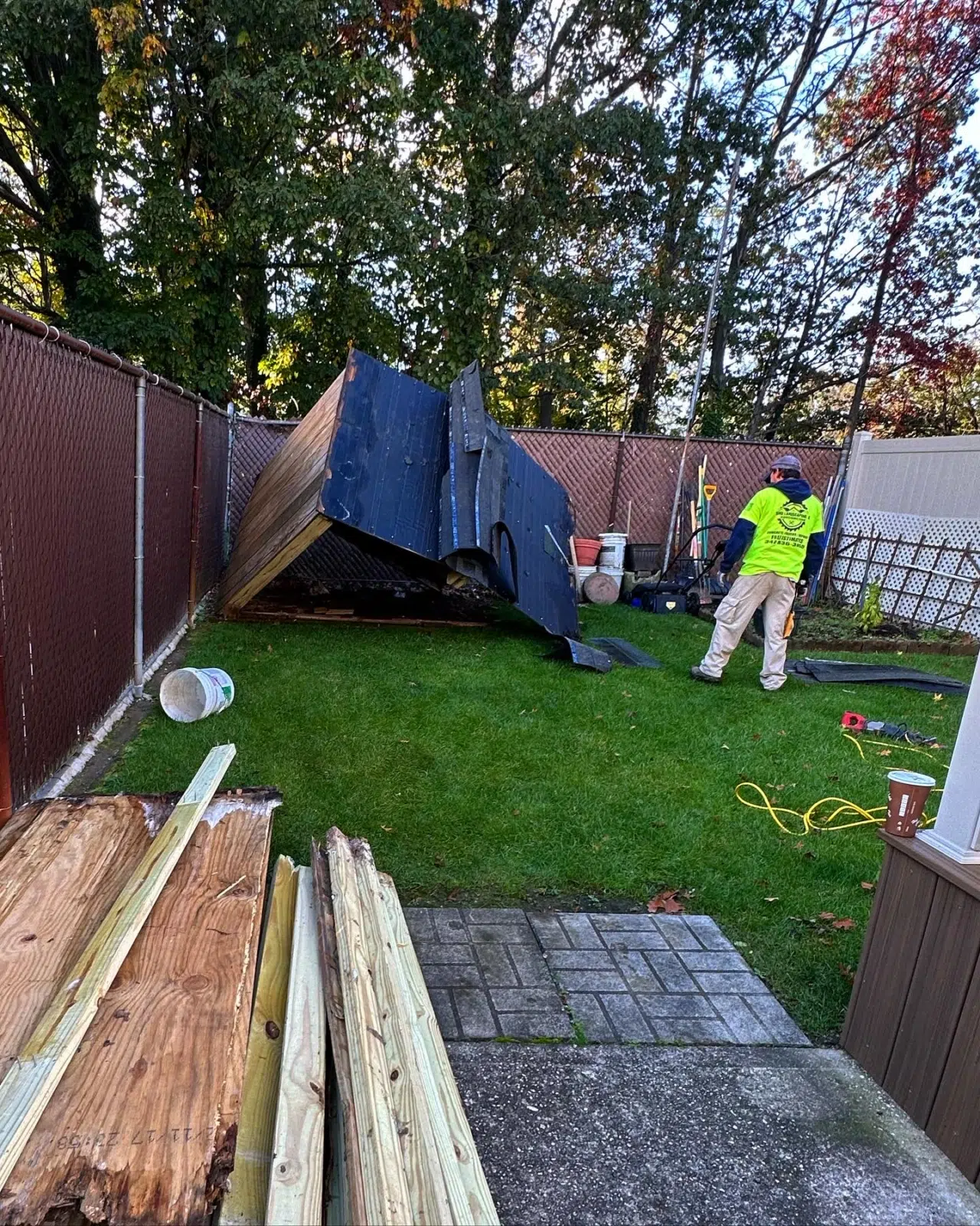 Worker in safety vest near collapsed shed debris in backyard — APPLE MASONRY INC in Brooklyn
