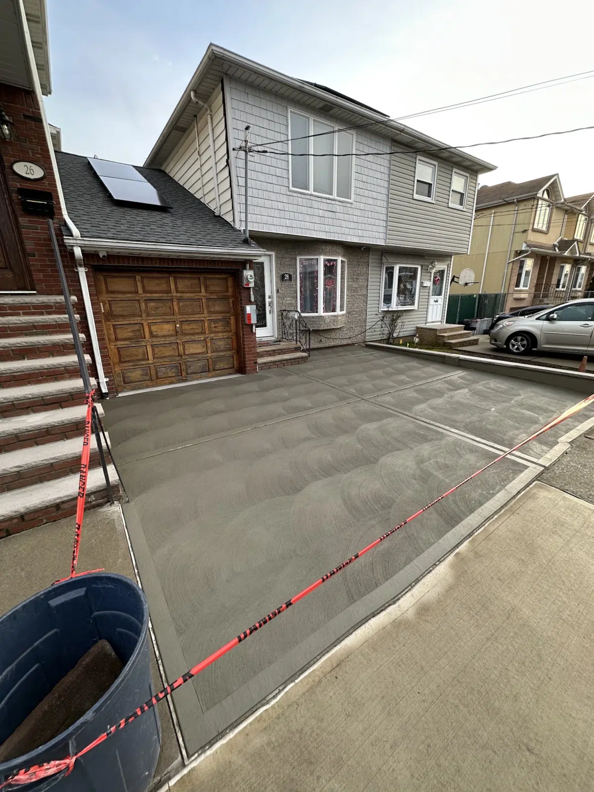 Freshly finished concrete driveway in front of a two-story house — APPLE MASONRY INC in Brooklyn